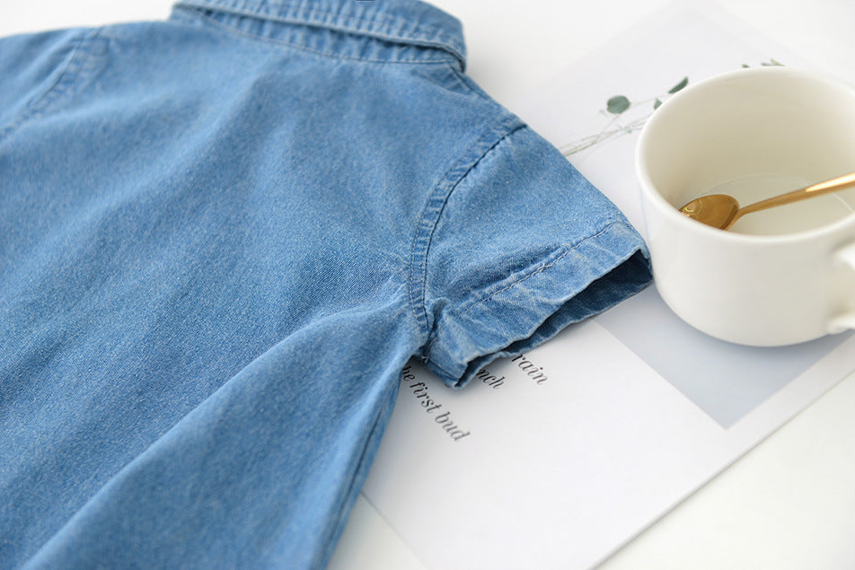 Blue boys denim shirt on a white surface with a white mug and spoon