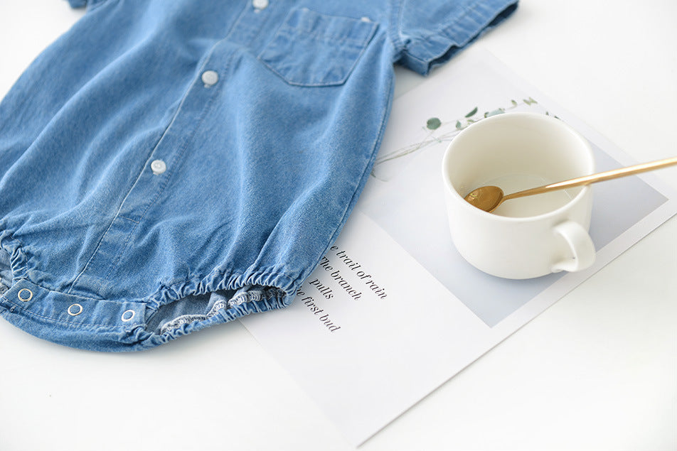 Blue boys denim shirt on a white surface with a white mug and spoon.