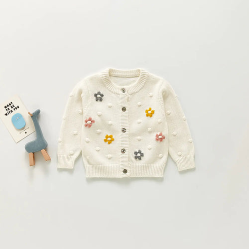 Children's white cardigan with floral embellishments on a light grey background