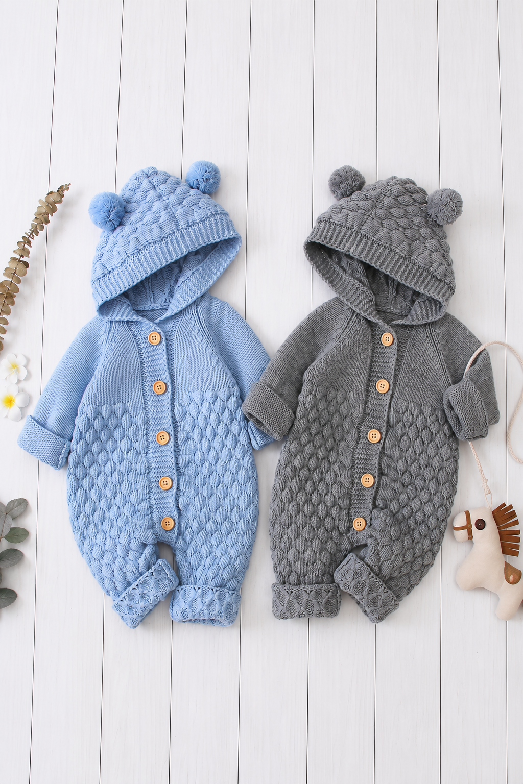 Baby cable knit hooded rompers in blue and grey featuring bear ear pom pom hoods, button-front fastening, textured knit detailing, and soft chunky fabric. Warm one-piece outfit for infants and toddlers.