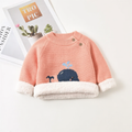 Coral pink sweater with whale design on a white surface