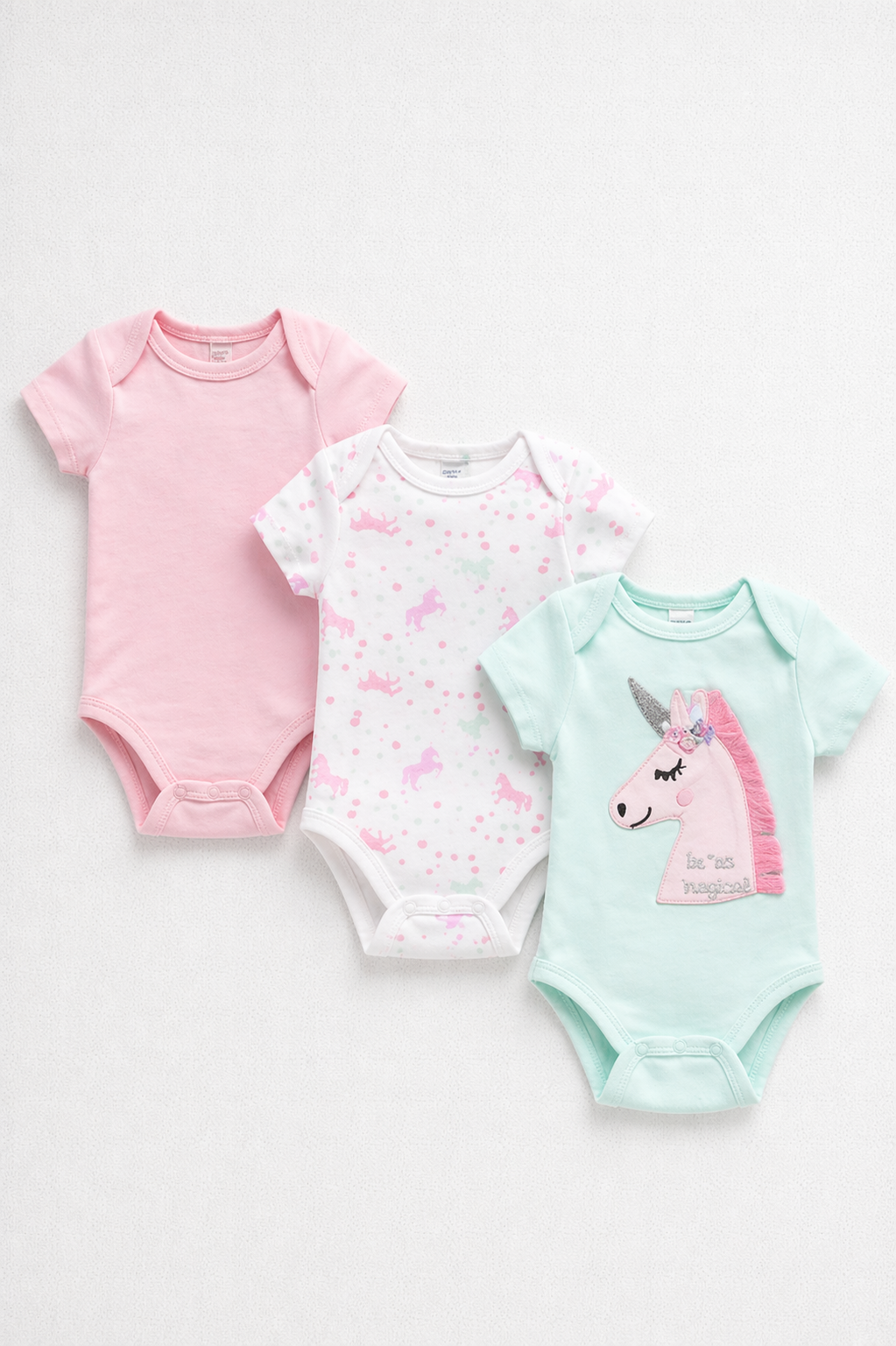 Three baby bodysuits with unicorn designs on a white background