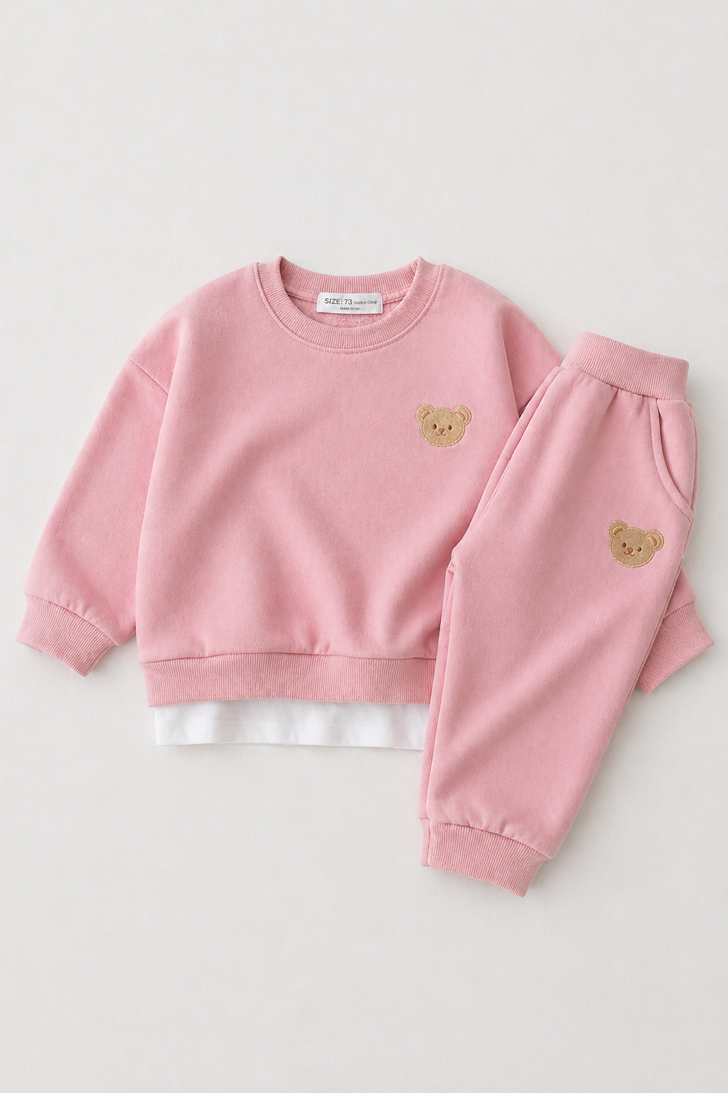Pink children's sweatshirt and pants set with bear designs on a white background