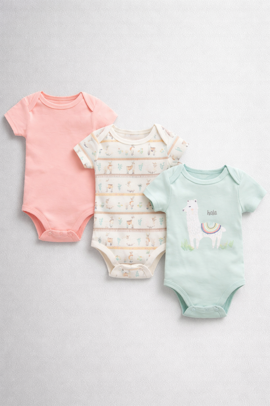 Three baby bodysuits in pink, white, and green with alpaca designs on a light gray background.