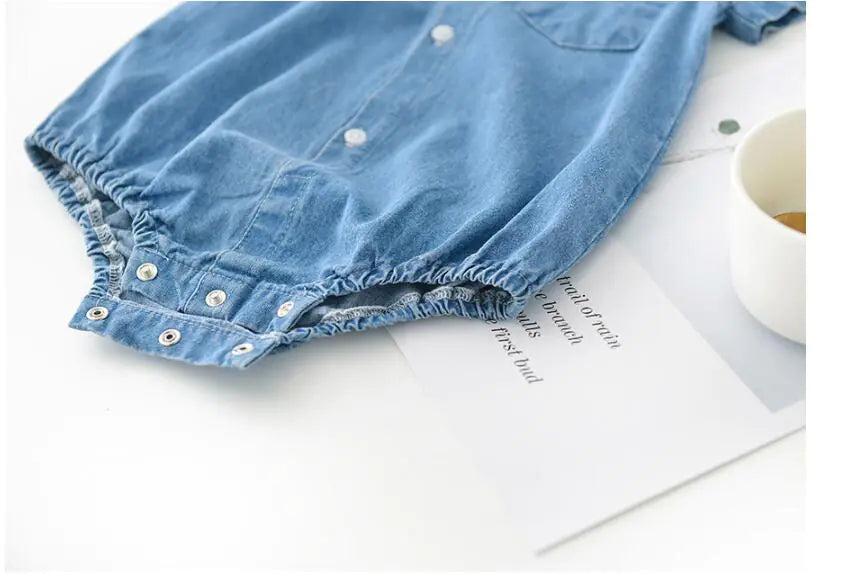 Close-up of a blue boys denim garment on a white surface with a magazine underneath.