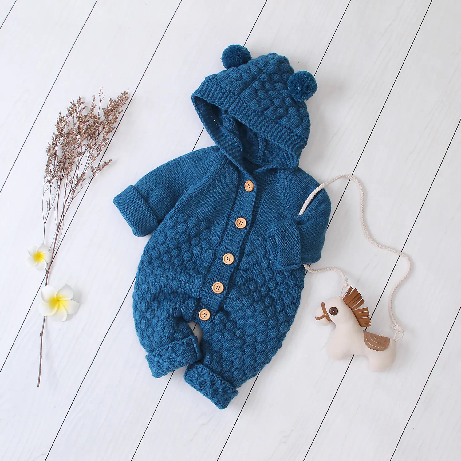 Navy blue knitted baby sweater with hood on a white wooden floor.