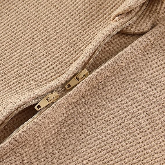 Camel baby onesie on a light beige background with a green leaf.