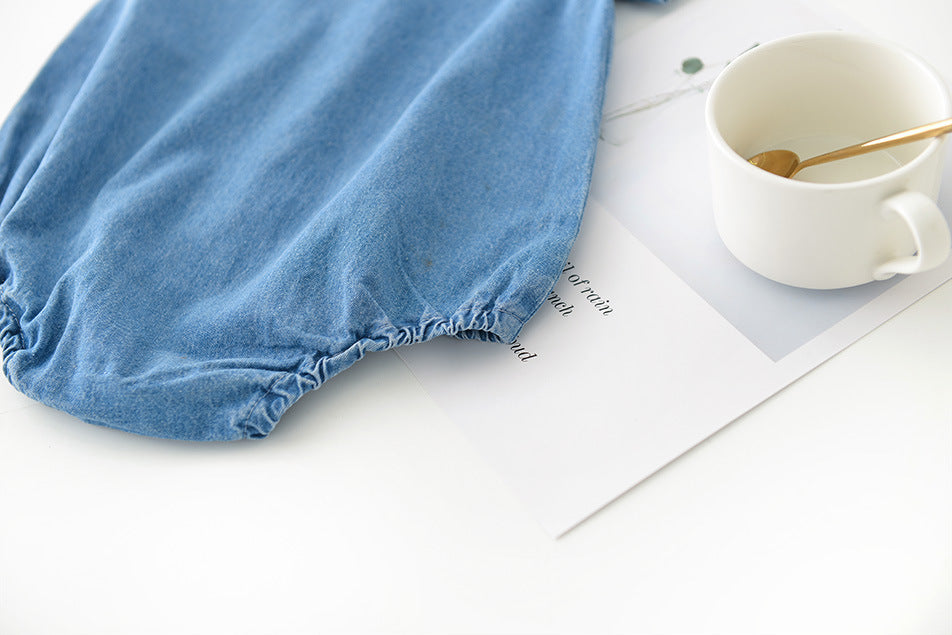 Blue boys baby bloomers on a white surface with a mug and spoon.