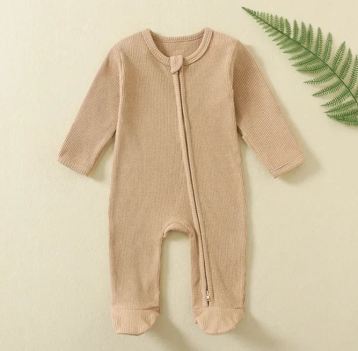 Camel baby onesie on a light beige background with a green leaf.